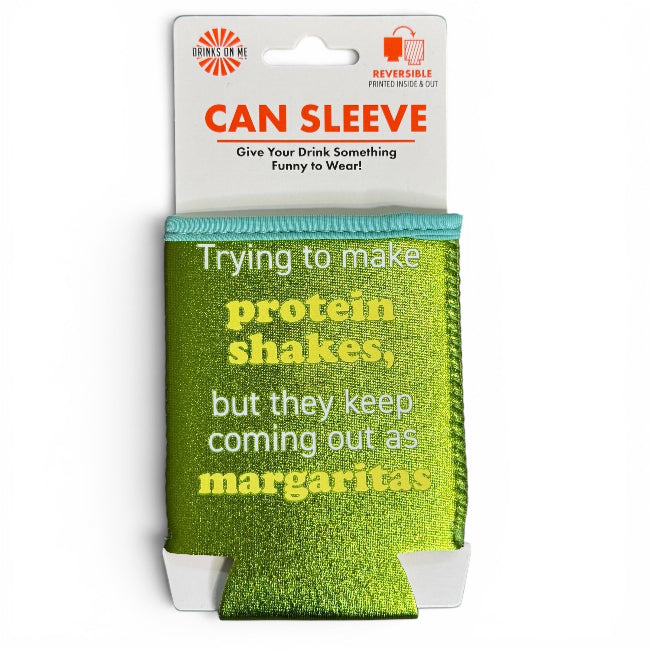 A green glittery can sleeve with humorous text reading 'Trying to make protein shakes, but they keep coming out as margaritas' in white and yellow lettering. The sleeve is attached to a white cardboard header card with 'Drunken Me' branding and features a hanger slot at the top.