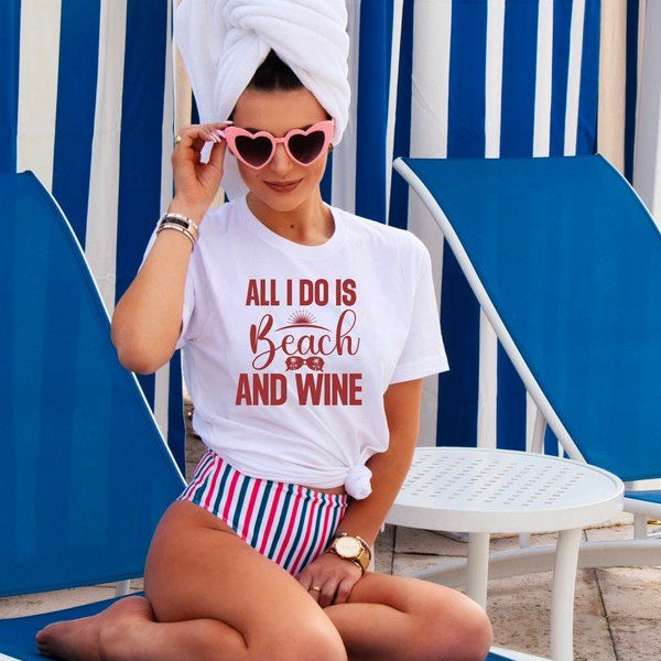 Woman sitting on a blue and white striped beach chair wearing a t-shirt with 'All I Do is Beach and Wine' text.