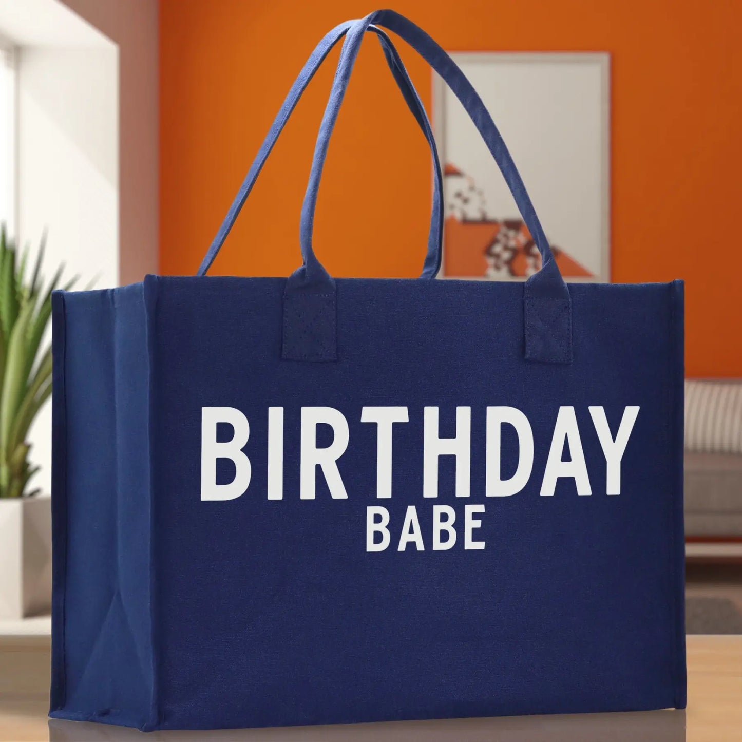 Blue tote bag with 'BIRTHDAY BABE' text on a neutral background