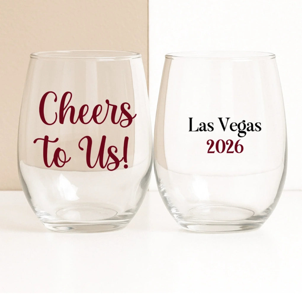 Two clear wine glasses with text 'Cheers to Us!' and 'Las Vegas 2026' on a white background.